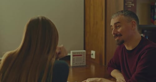 Young Man Sits at a Table with a Woman and Communicates Nicely with Her a Meeting in the Library