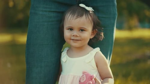 Adorable Child Smiles Holding Pink Toy Outdoors