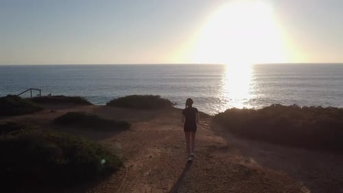 Woman Runs Toward Ocean at Sunrise
