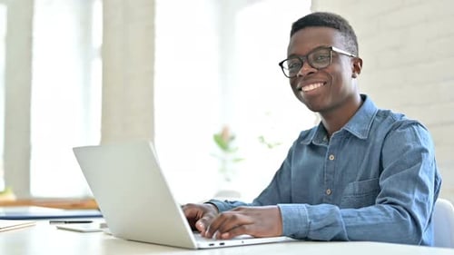 Young Adult Types on Laptop and Smiles