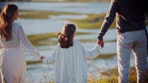 Young Family Standing on the Wheat Field and Holding Hands While Looking at River