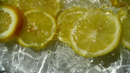 Lemon Slices Falling into Refreshing Clear Water