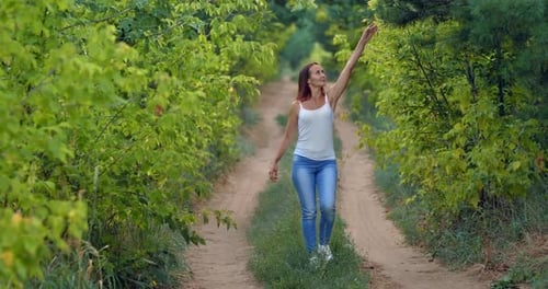 Young Woman is Walking Along a Path in the Forest Enjoying Nature