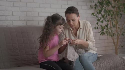 Woman and Child Knitting Together Indoors