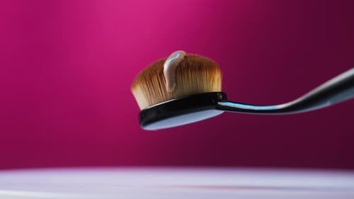 Pouring Foundation Tone on Brush on Pink Background