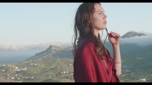 Side View of a Woman Walking Along the Top of a Hill in the Rays of the Sunset Against the