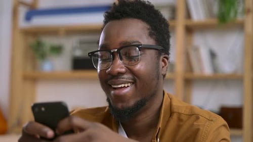 Smiling Man Using His Phone in a House