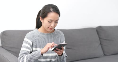 Woman Using Smartphone on Sofa Indoors