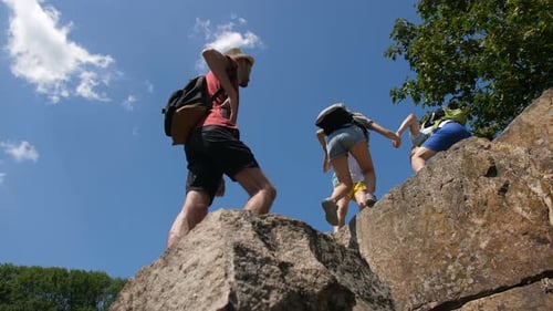 Des randonneurs aident leurs amis à grimper au sommet d'une montagne