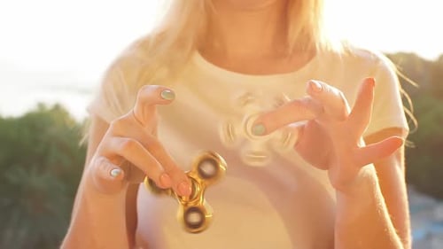 Fille jouant avec Fidget Spinner au coucher du soleil.