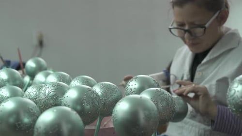 Woman Decorates Green Christmas Ornaments in Workshop