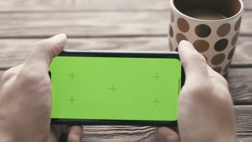 Man Using Smartphone with Green Screen During Coffee Break