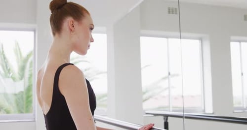 Caucasian female ballet dancer practicing up by the mirror for dance class in a bright studio