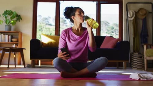 Woman Drinks Water, Uses Phone After Yoga