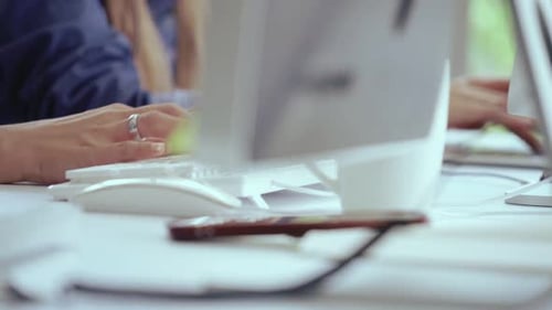 Nahaufnahme einer Geschäftsfrau, die auf dem Schreibtisch mit der Hand tippt und am Computer arbeitet