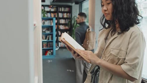 Studentin liest Buch in der Bibliothek