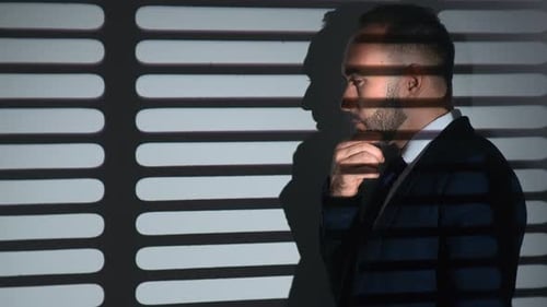 Thoughtful Man in a Dark Suit Standing in Shadows
