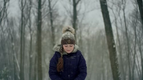 Kind spielt im Winter im Park Tosses Snow Up. Wirft Schneeflocken und lächelt in einem Winterpark