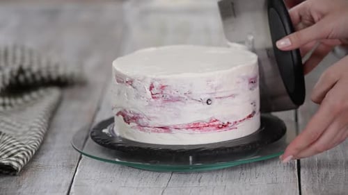 Baker Frosts a Cake with White Frosting