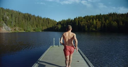 Man Run on Dock To Jump in Cold Mountain Lake