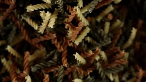 Rotini Pasta Macaroni vole après avoir explosé. Tas de pâtes multicolores Bouncing Black Bg
