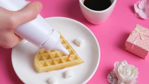 Close Up View on Home Made Heartshaped Waffle Topped with Strawberry Syrup a Cup of Coffee and a