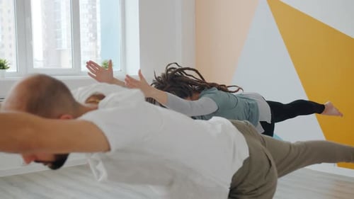 Yoga Students Male and Female Concentrated on Balancing Asanas in Cozy Studio