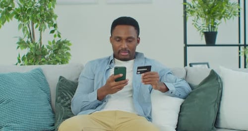 Young Man Uses Credit Card for Mobile Payment