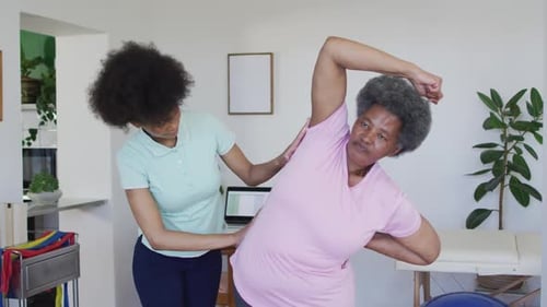 Physical Therapist Assisting Senior Woman with Stretching