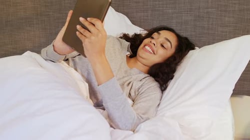 Woman Using Tablet Device While Lying in Bed