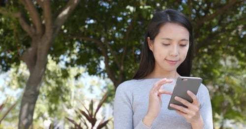 Woman Uses Smartphone in Sunny Urban Park