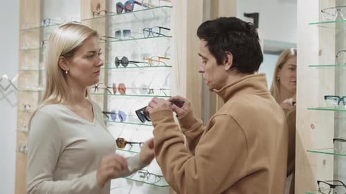 Female Optometrist Helping Man Choosing Sunglasses