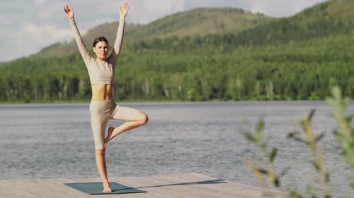 Woman Practices Yoga Tree Pose by the Lake