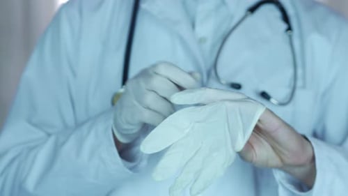 Doctor Putting On Gloves in Preparation for Procedure