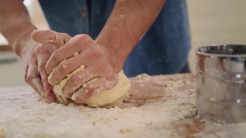 Handheld video shows of man kneading dough in the kitchen. Shot with RED helium camera in 8K