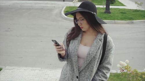 Attractive Young Woman Using Modern Smartphone Outside on Urban Street
