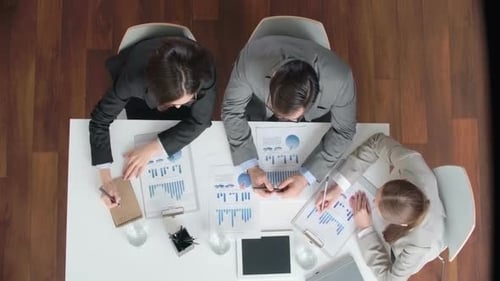 Professionals Reviewing Charts at a Table Together