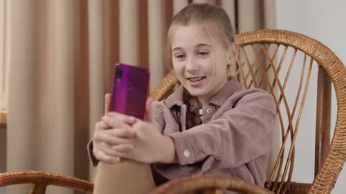 Girl Chatting on Phone in Wicker Chair