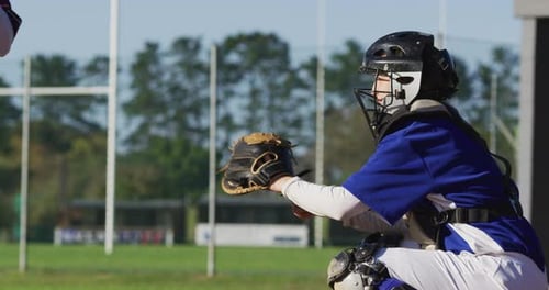 Kaukasische Baseballspielerin in Fängerposition fängt Ball auf Baseballfeld