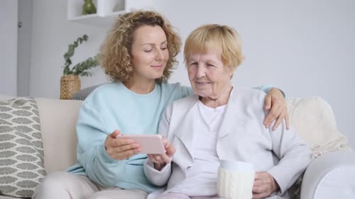 Grandmother and Adult Daughter Watching Smartphone at Home