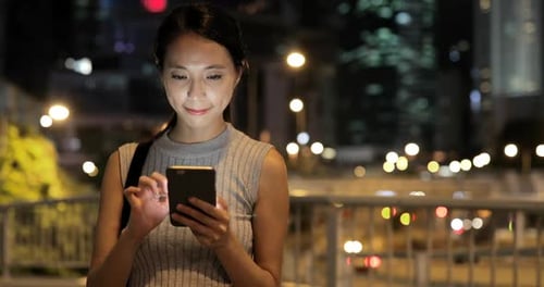Woman Uses Smartphone at Night in the City
