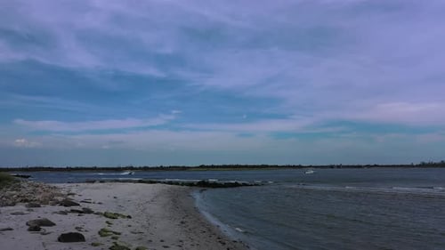 A low angle drone shot of an empty beach on a sunny day. The camera dolly out slowly over the sand.