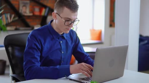Young Man Working on Laptop in Bright Office