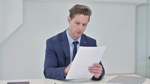 Adult in Blue Suit Holding Paper at Desk