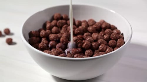 Milk Pouring onto Chocolate Cereal in Bowl