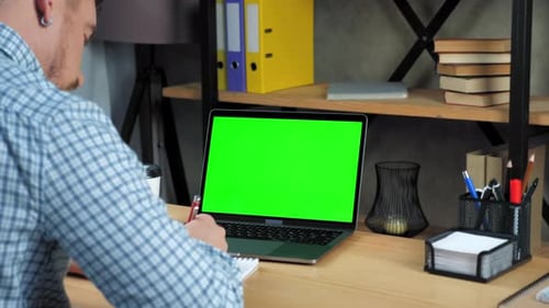 Green screen laptop concept: Businessman at office sits table writes in notebook