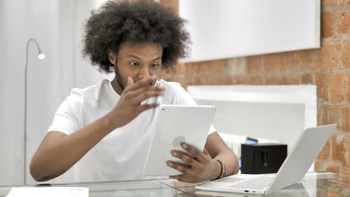 Frustrated Young Adult Using Tablet at Desk