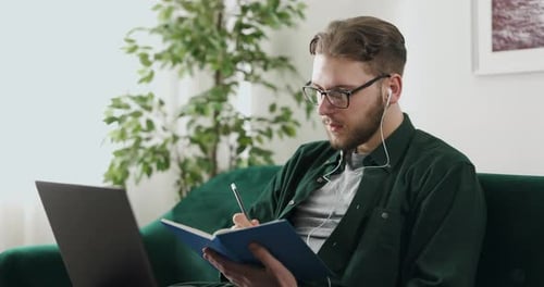 Young Adult Works at Home With Laptop and Notebook