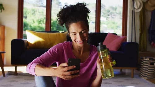 Woman Drinking Water While Using Smartphone