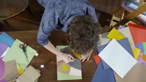 Person Creating Abstract Art With Paper On Table